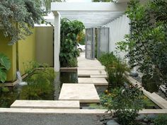 an outdoor garden with water features and plants on either side, along with stepping steps leading up to the front door