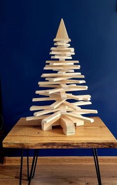 a wooden christmas tree sitting on top of a table in front of a blue wall