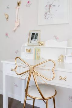 a white desk with a gold bow on it's top and some pictures above it