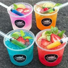 four different colored drinks with strawberries and lemons