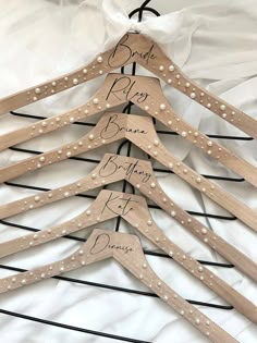 wooden clothes hangers with names on them sitting on a white sheet covered bedding