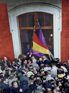 a large group of people standing in front of a building with a flag on it