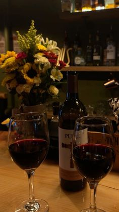 two glasses of wine sitting on top of a wooden table