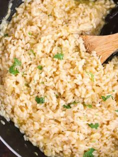 cooked rice in a skillet with a wooden spoon and parsley on the side