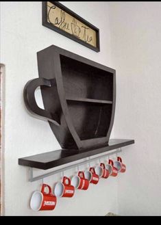 there is a coffee cup on the shelf with cups hanging from it's hooks