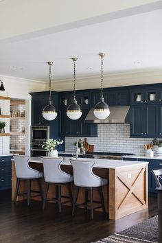 a kitchen with blue cabinets and white counter tops is pictured in this image, there are four bar stools at the center of the island