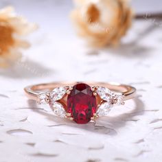 a close up of a ring with a red stone and two white stones on it