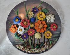 there are many different flowers on this circular wall decoration, which is made out of wood