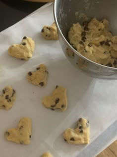 cookie dough with chocolate chips in the middle and a metal bowl next to it on a table