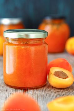 a jar filled with oranges sitting on top of a wooden table next to sliced oranges