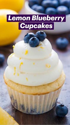 a cupcake with white frosting and blueberries on top next to lemons