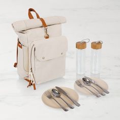 a white backpack sitting on top of a table next to silverware and utensils