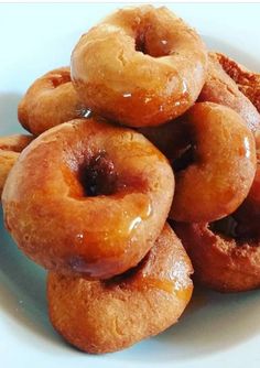 a pile of doughnuts sitting on top of a white plate covered in syrup