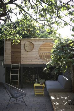 an outdoor living area with a couch, table and ladder in the middle of it