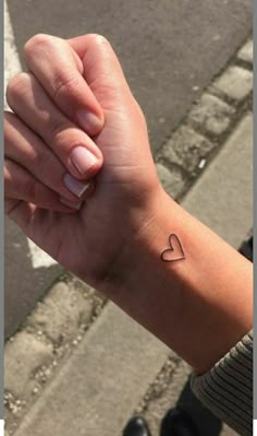 a woman's arm with a small heart tattoo on the left side of her wrist