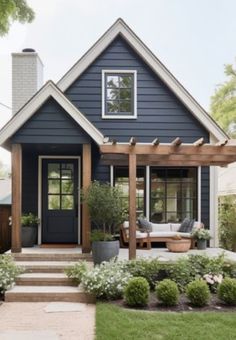 a blue house with white trim and wooden steps leading up to the front door is surrounded by greenery