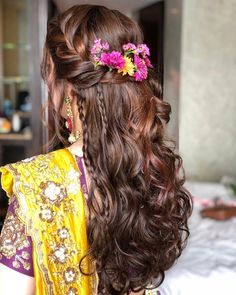 the back of a woman's head with long hair and flowers in her hair