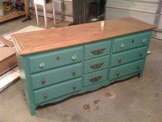 a green dresser with wooden top in a garage