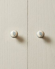 two white door knobs with blue designs on the front and back of each one