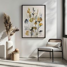 a white room with a chair, vase and painting on the wall next to it