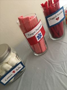 two glass vases filled with red and white marshmallows on top of a table