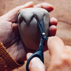 someone is holding scissors and making something out of clay