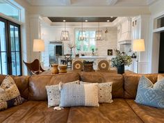 a living room filled with lots of furniture and pillows on top of a brown couch