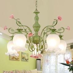 a green chandelier hanging from the ceiling in a living room with pink flowers