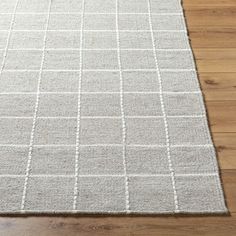 a white rug on top of a wooden floor next to a wood flooring board