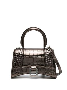 Hourglass XS croc-embossed tote bag from BALENCIAGA featuring bronze-tone, calf leather, embossed crocodile effect, monogram plaque, adjustable detachable shoulder strap, single circular top handle and foldover top with magnetic fastening.Width 7,48 in / 19 cm Height 4,72 in / 12 cm Depth 2,36 in / 6 cm Handle 2,76 in / 7 cm Balenciaga Tote, Balenciaga Women, Brown Shoulder Bag, Balenciaga Bag, Browning, Leather Tote Bag, Leather Top, Womens Tote Bags, Embossed Leather