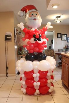 a santa clause balloon sitting on top of a pile of balloons in the middle of a kitchen