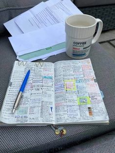 a coffee cup and pen sitting on top of an open book