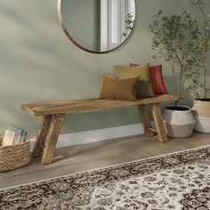 a wooden bench sitting in front of a mirror next to a potted plant on top of a rug