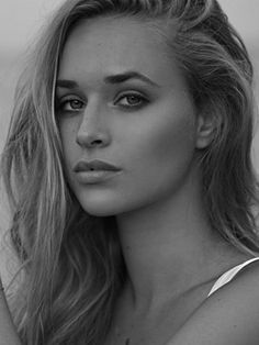 a woman with long blonde hair posing for a black and white photo on the beach