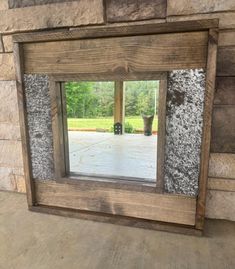 a mirror sitting on top of a wooden floor next to a stone wall with a potted plant in it