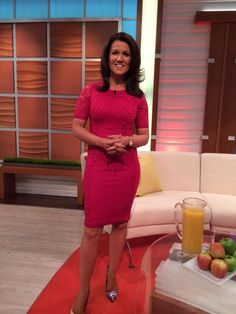 a woman in a pink dress is standing on a red carpet near a couch and coffee table