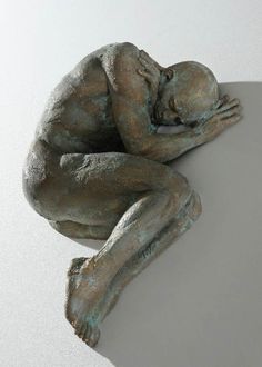 a bronze statue sitting on top of a table next to a white wall and floor