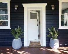 two large planters on the front porch of a house with blue siding and white trim