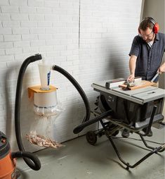 a man is using a table saw to cut wood with a power drill and an orange blow dryer