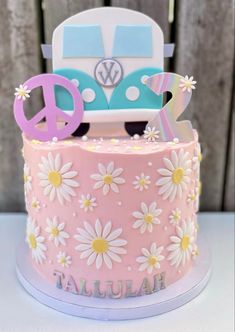 a pink and blue cake decorated with daisies, peace sign, and volkswagen van