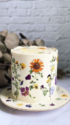 a white hat with flowers on it sitting on top of a plate next to a brick wall