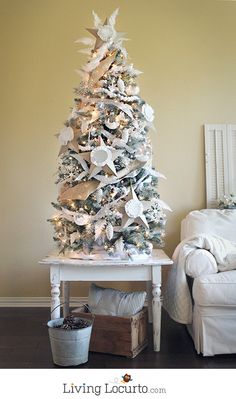 a white christmas tree in a living room with star decorations on the top and bottom