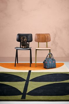 two chairs sitting next to each other in front of a rug with a dog on it