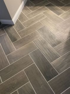 a bathroom with grey tile flooring next to a toilet and bathtub in the corner