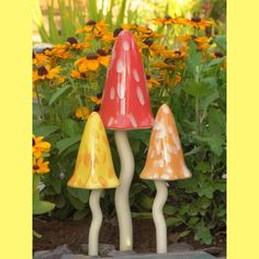 three small ceramic lamps sitting on top of a rock in front of some yellow flowers