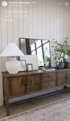 a large mirror sitting on top of a wooden dresser next to a lamp and vase