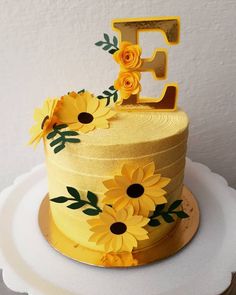 a yellow cake with sunflowers and the letter e on it's top