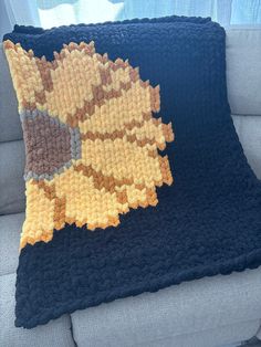 a crocheted pillow sitting on top of a couch next to a blue blanket