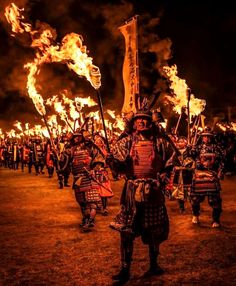 a group of people dressed in costume and holding fire sticks at night with flames coming from them