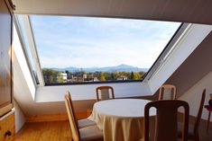 a dining room with a table and chairs in front of a window overlooking the mountains